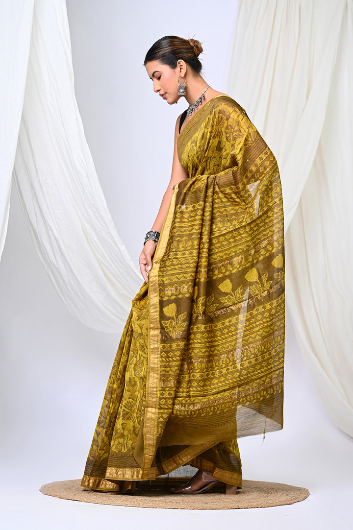 Side-profile view of a woman elegantly posing in a natural mustard yellow Maheshwari silk saree featuring a handblock printed geometric design and a patterned pallu.